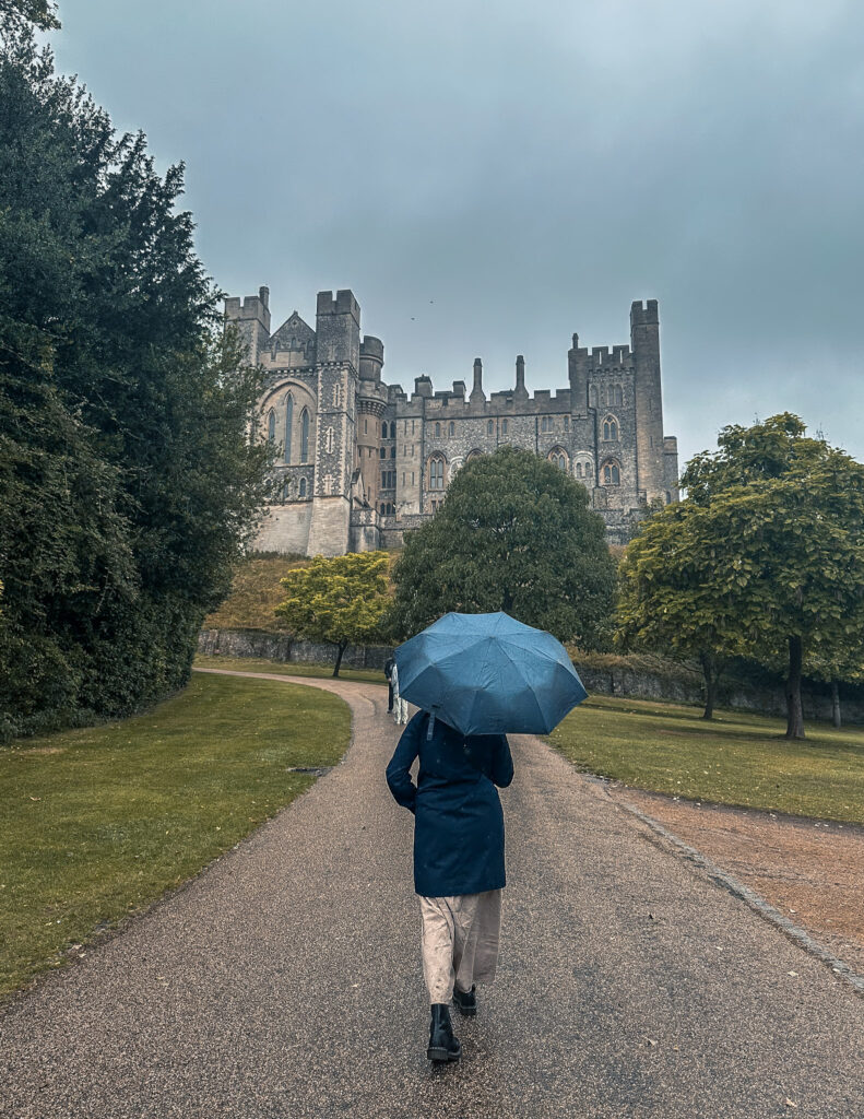 Eu andando com guarda-chuvas com o castelo ao fundo